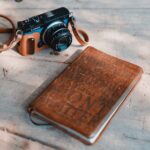 Camera and journal rest on a wooden surface.